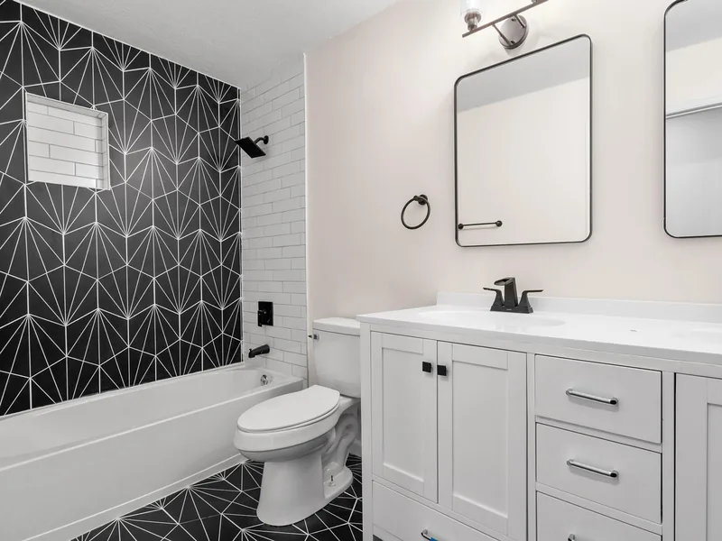Finished hall bath with a geometric black tile accent wall